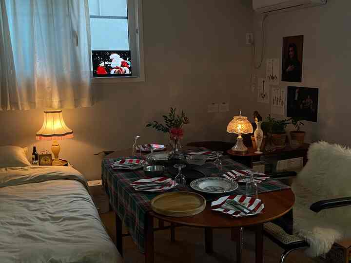 ホワイトと木目調が調和したダイニングルーム、クリスマスのテーブルセッティングと居心地の良いアームチェアが配置された温かみのあるインテリア