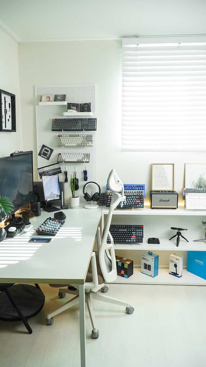 ホワイトとブラックを基調としたモダンなホームオフィス、多数のキーボードと整然としたデスク配置が印象的な空間