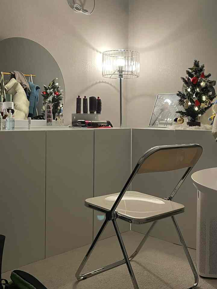 白を基調とした小さな部屋、化粧台とフロアランプ、クリスマスのミニツリーが配置されたシンプルなインテリア