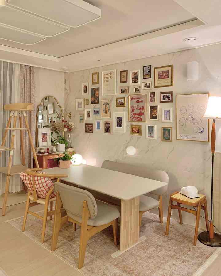 ベージュと木目調のダイニングルーム、多数の額縁が壁に飾られ、温かみのあるシンプルな雰囲気のインテリア