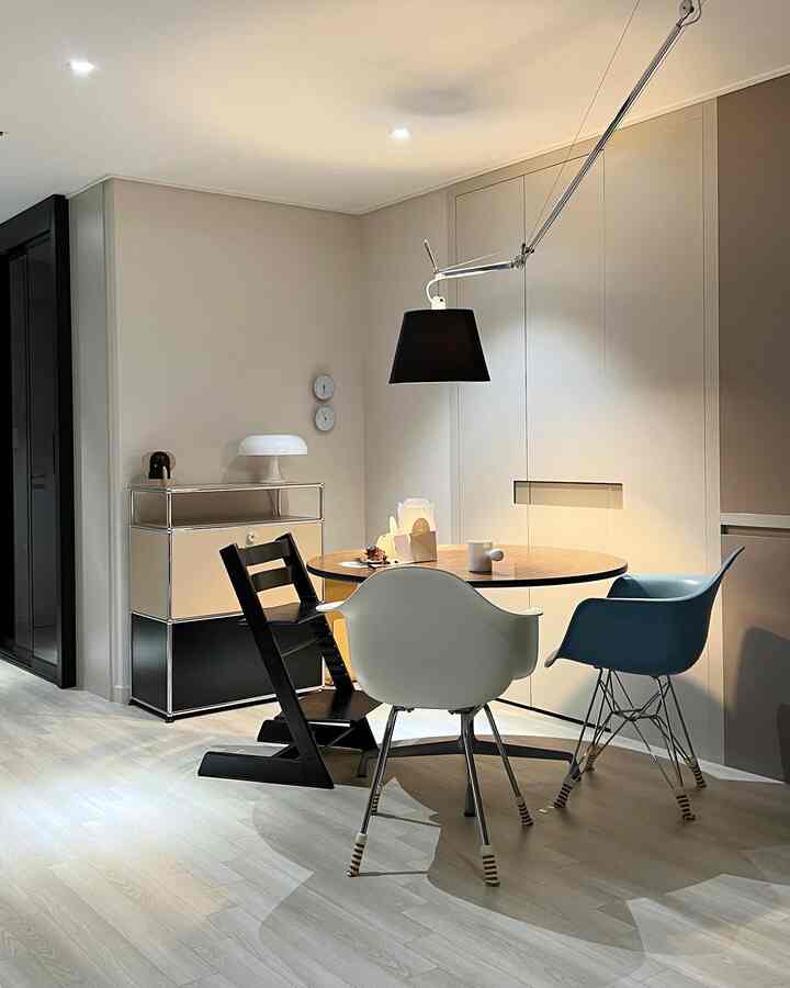 Light brown and white toned modern dining room featuring a round dining table, three chairs, and a pendant light in a clean setting