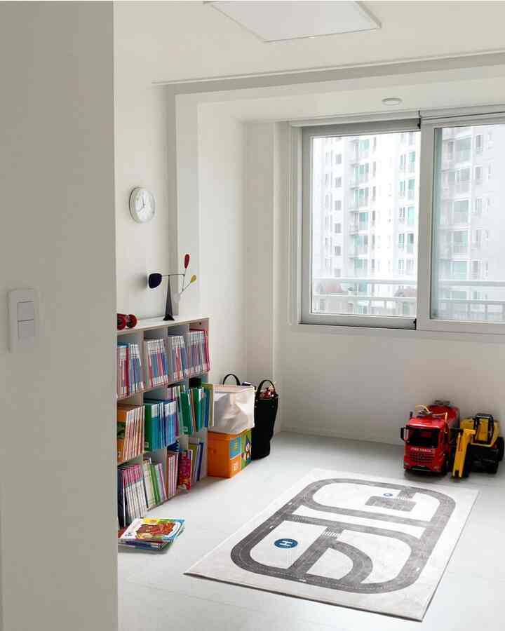 Bright kids' room in white tones featuring road playmat and bookshelf neatly arranged