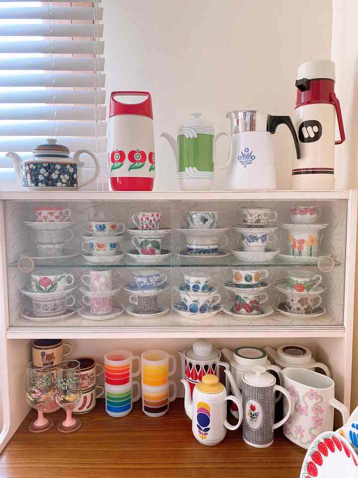 White and red toned kitchen featuring a variety of vintage bowls and teacups displayed in a cozy vintage kitchen setting