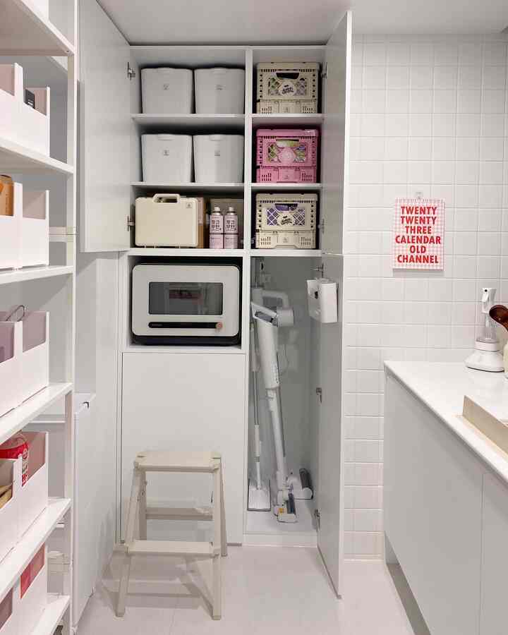 白を基調としたキッチン収納スペース、整理された収納箱と家電が配置されたコンパクトな空間
