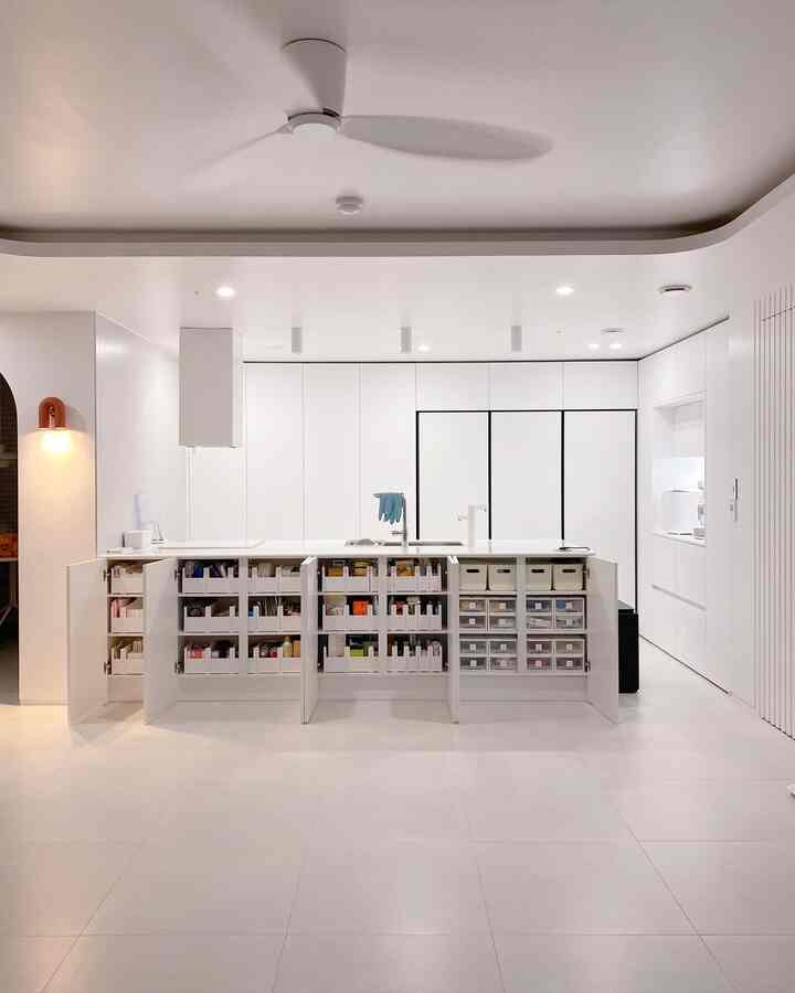 White-toned kitchen space featuring wide cabinets and open organized storage with a modern, clean interior design