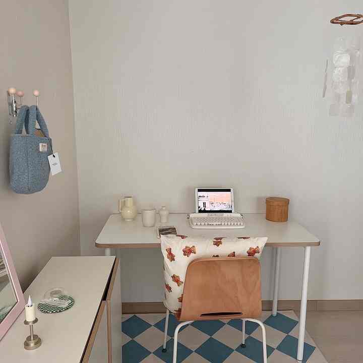 A compact home office in natural and white tones featuring a wooden chair and teddy bear cushion for a cozy atmosphere