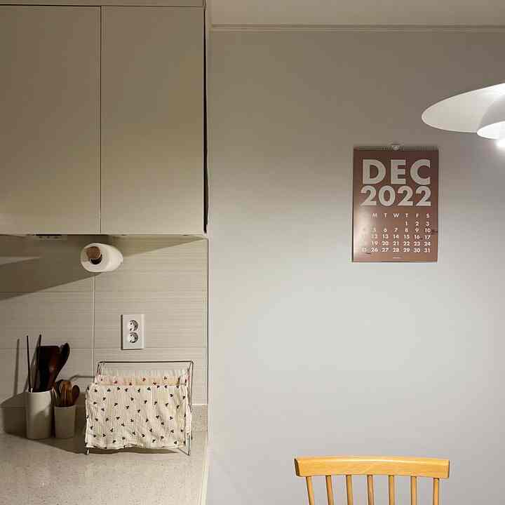 ナチュラルトーンのキッチン、木製の椅子とタオル掛けが配置された清潔感のある空間