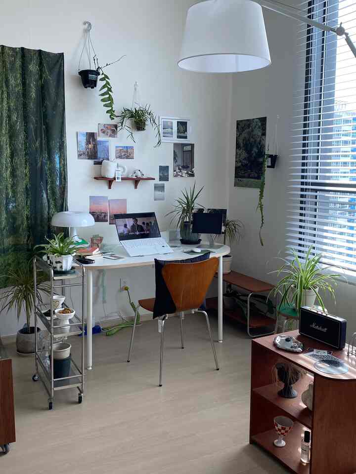 白と木目調が調和したホームオフィス空間、デスクと複数の植物が配置された印象的でナチュラルなワークスペース