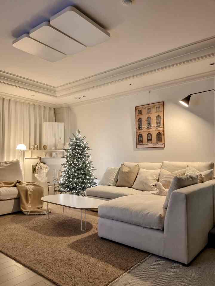Soft beige and white tone living room featuring a Christmas tree and large sectional sofa with cozy atmosphere