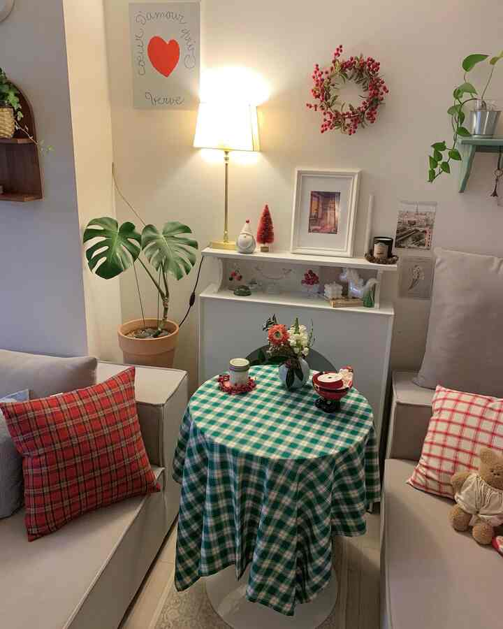 A cozy living room featuring red and green tones with checkered cushions, plants, and warm lighting