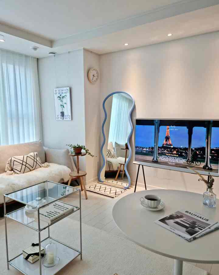 Mid-Century Modern living room in white and light brown tones, featuring a unique full-length mirror and Samsung TV for a harmonious space
