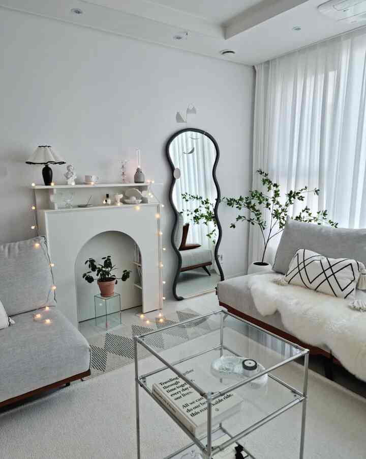 White and gray toned living room featuring an irregular-shaped mirror and string lights, decorated in a modern and calm style