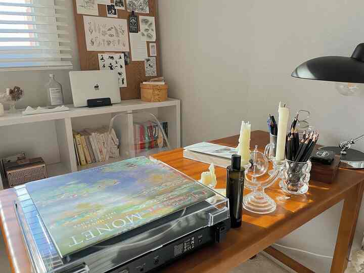 白と木目調の調和が取れたホームオフィス、デスクの上にノートパソコンとキャンドルが置かれたシンプルで温かみのあるインテリア