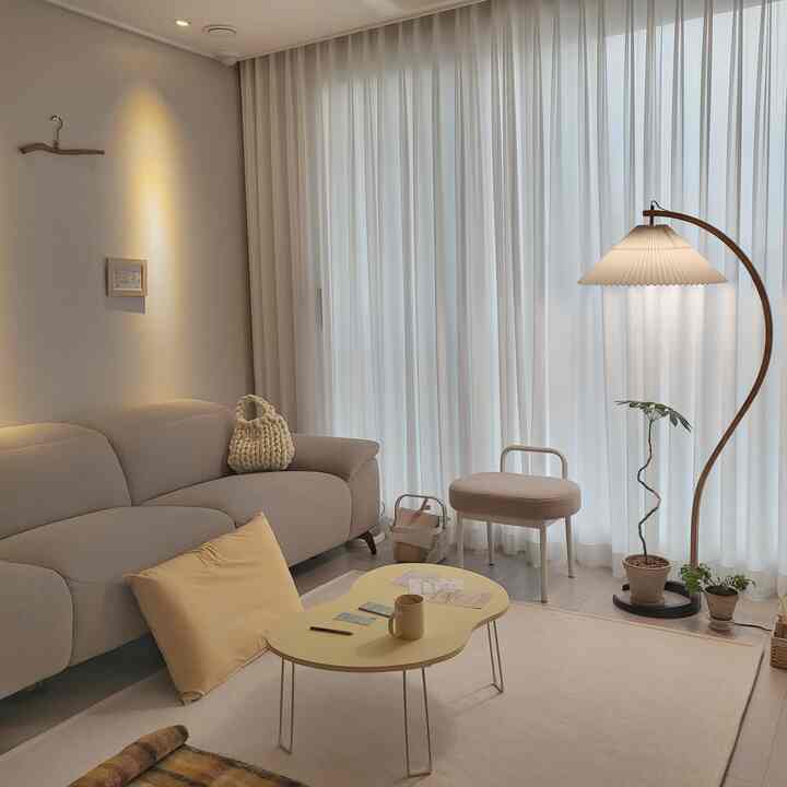 Beige and wood tone living room featuring curtains and a floor lamp with a natural modern style atmosphere