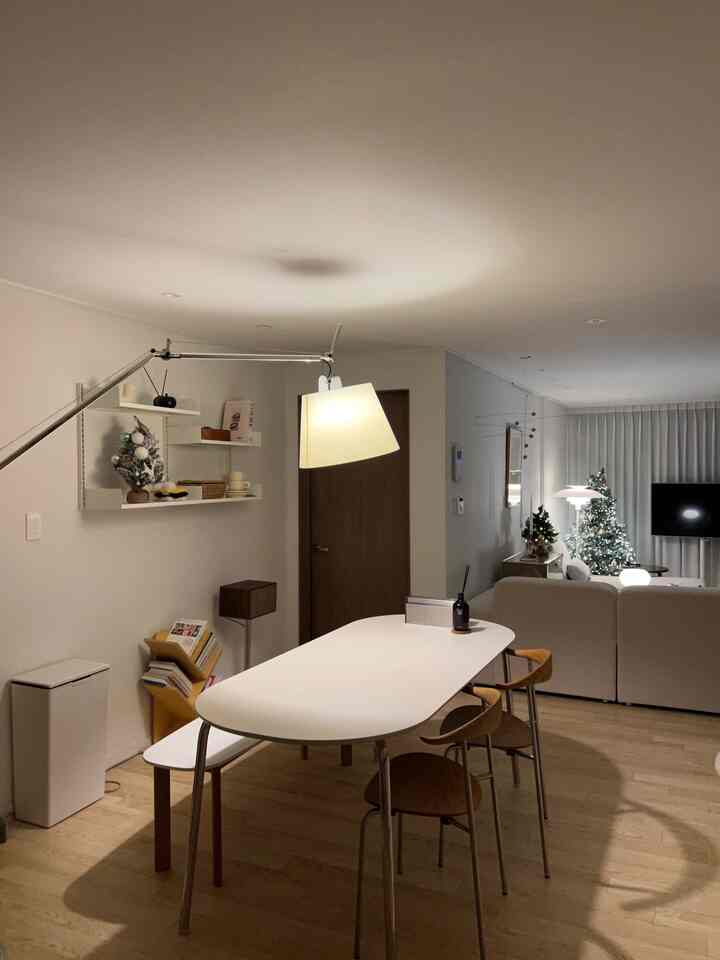 白とナチュラルな色調のキッチンとリビング、モダンなダイニングテーブルと椅子が配置された温かみのあるインテリア