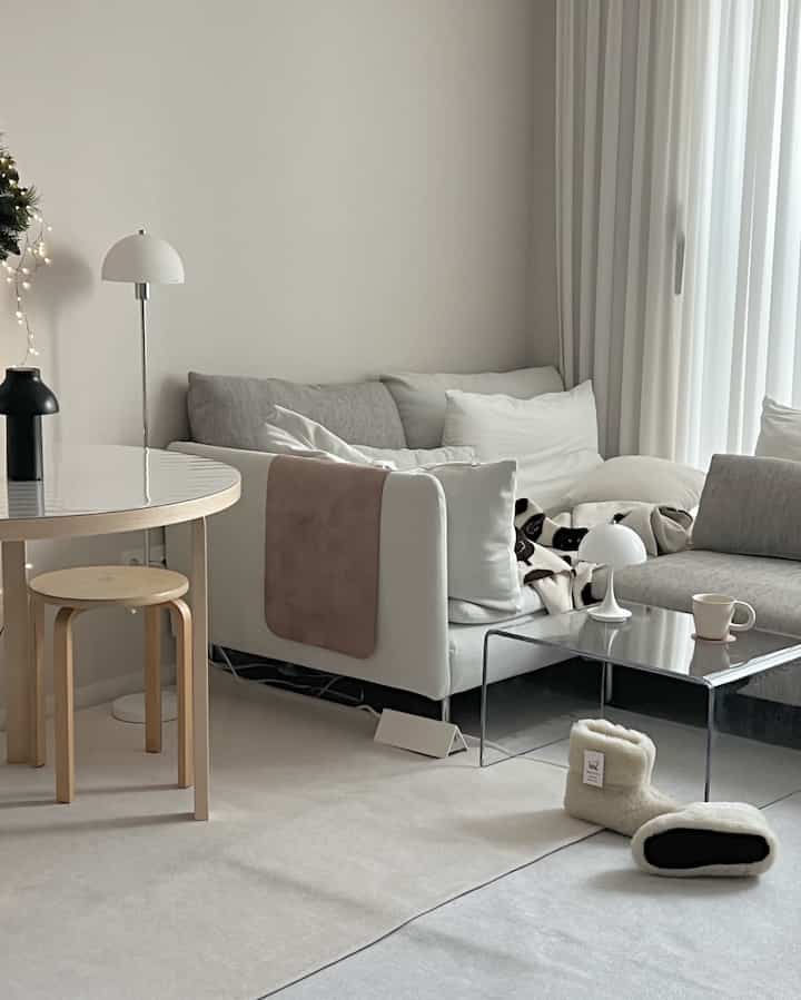 Natural modern toned living room featuring a white sectional sofa and transparent acrylic coffee table with a calm atmosphere