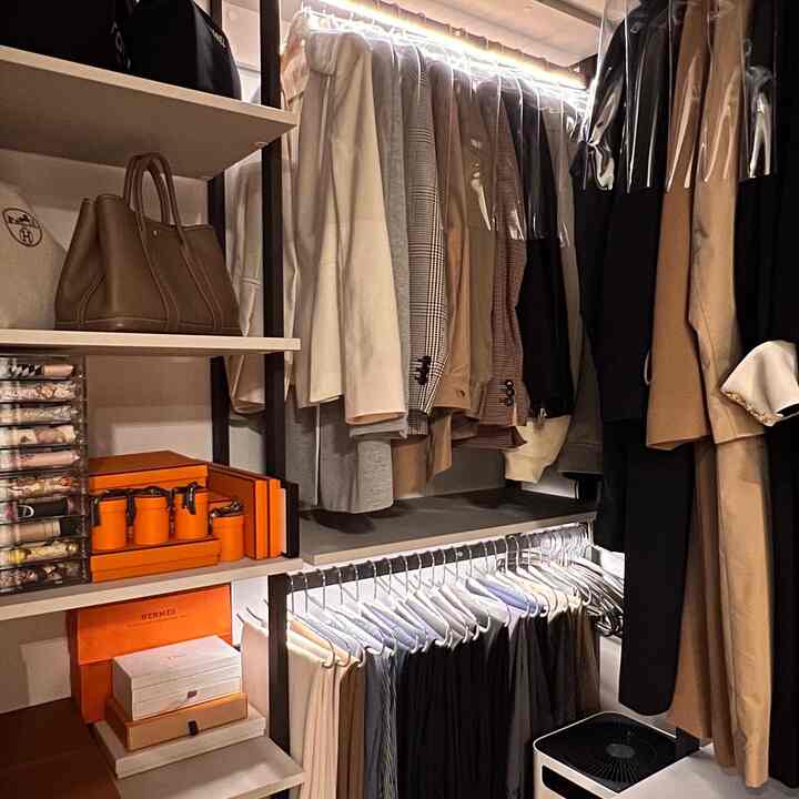 ブラウンとアイボリーのトーンが特徴の2坪のウォークインクローゼット、整理されたハンガーと透明な引き出しが配置された落ち着いた空間