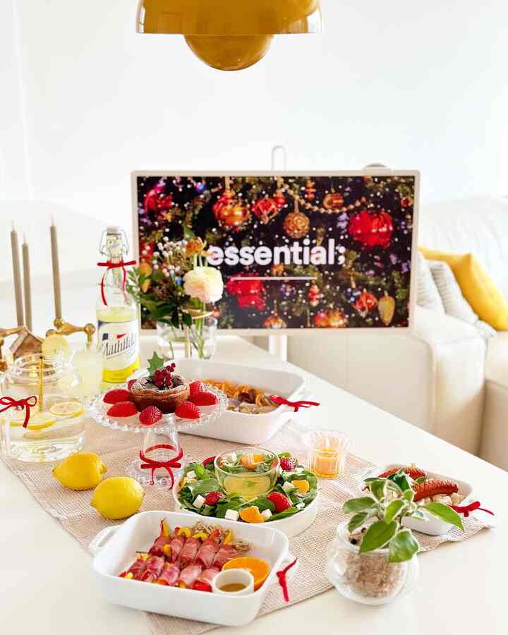 White and red-toned living room dining table featuring Christmas decorations and party dishes with warm home party atmosphere