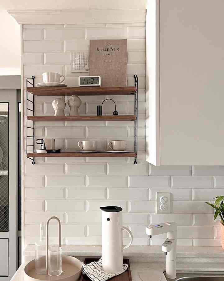Clean kitchen space with white tiled walls and wooden shelves, featuring a modern and natural atmosphere