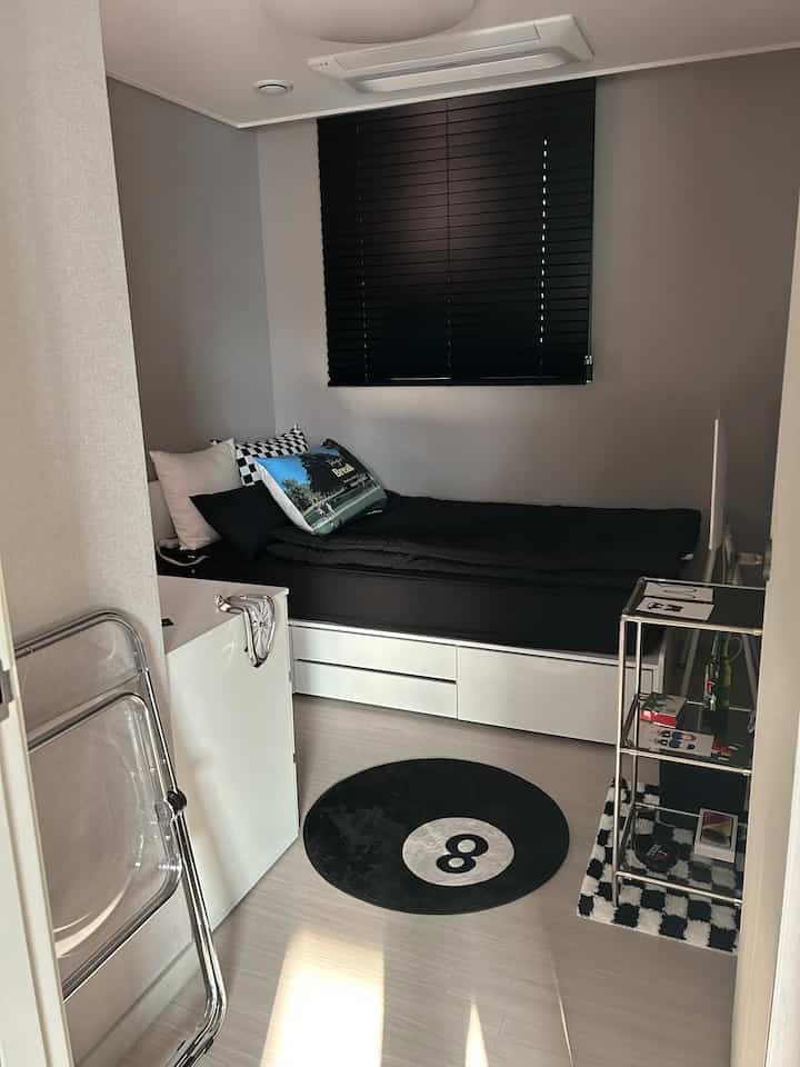 Monotone black and white small compact single bedroom featuring a bed and tidy shelving with minimal interior style