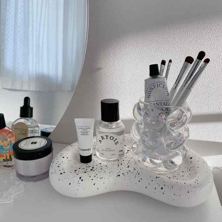 ホワイトの壁を背景に、斑点模様のトレイと透明なブラシスタンドが配置された清潔感のあるパウダールームのインテリア