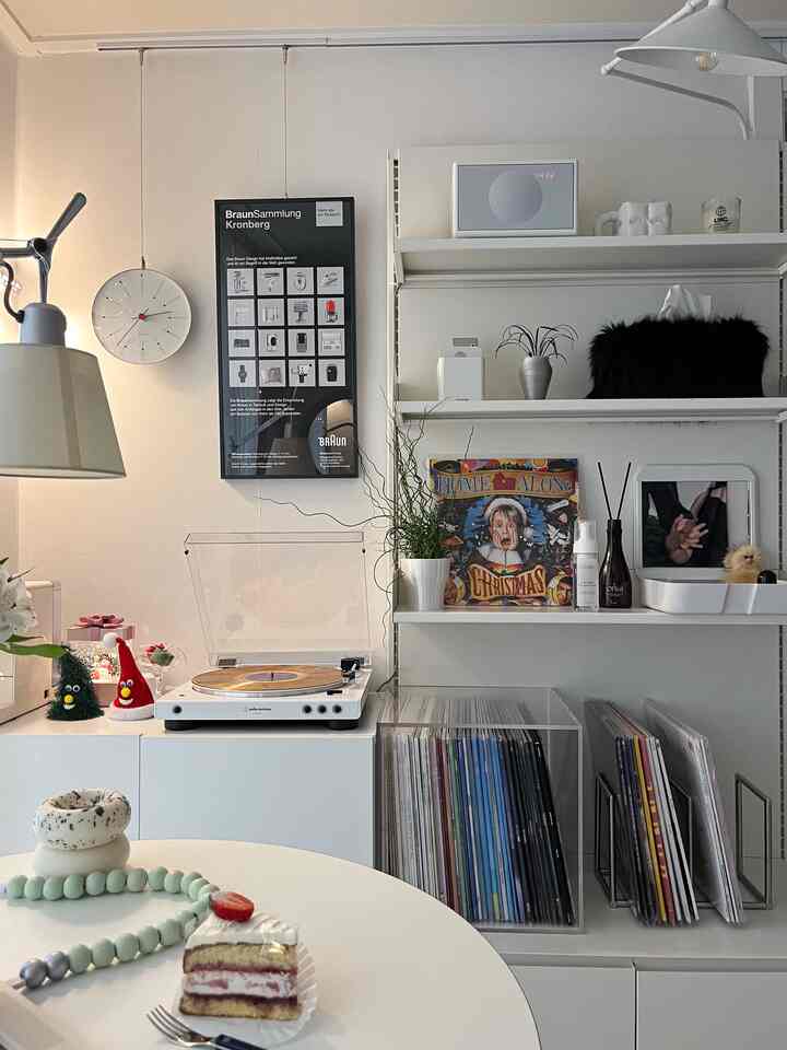 White-toned home cafe space featuring an Audio-Technica turntable, LP storage, a wall clock, and framed artworks with a cozy atmosphere
