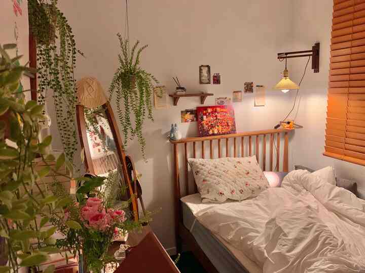 ナチュラルな色調の寝室、木製ベッドと棚、さまざまな植物やヴィンテージミラーが配置された雰囲気のあるインテリア