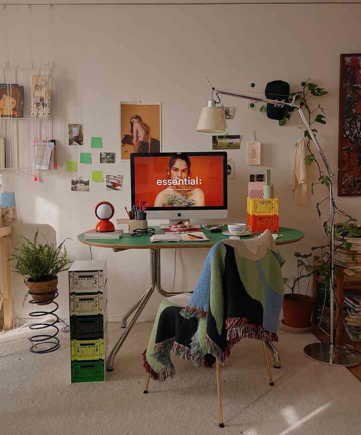 A beige-toned home office featuring a mid-century modern desk, plants, and various decorative items creating a cozy workspace