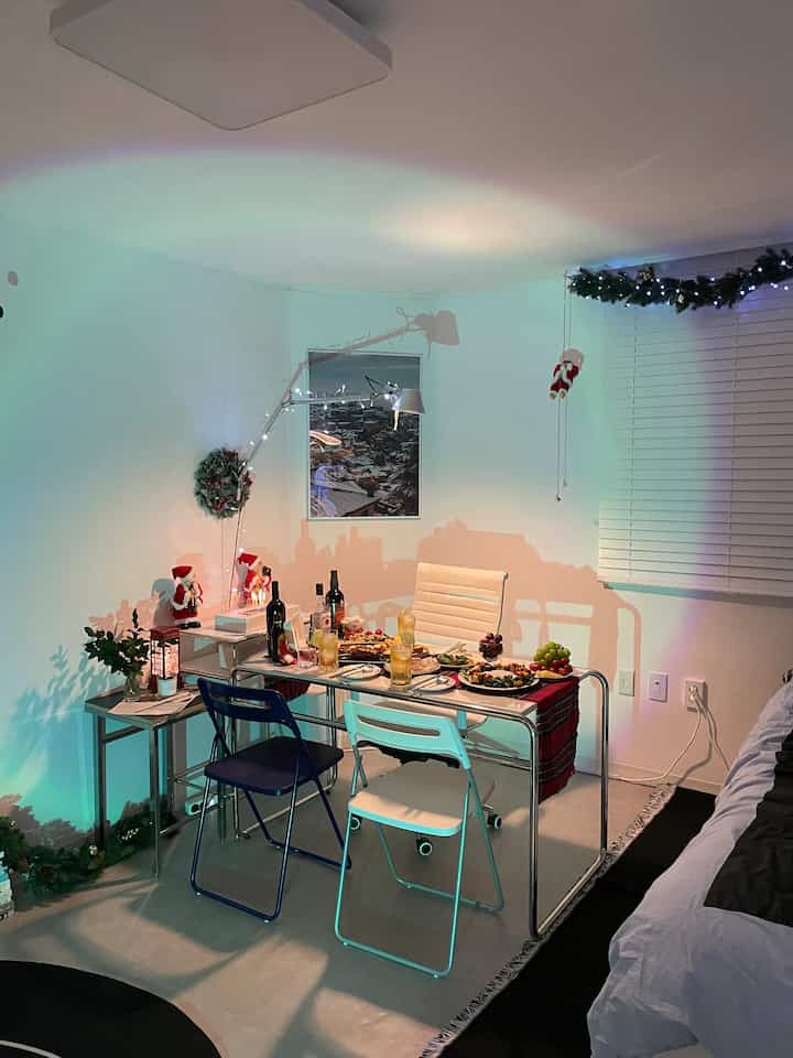 White-walled studio living room with blue chairs, featuring Christmas decorations and a festive dining table in a cozy setting