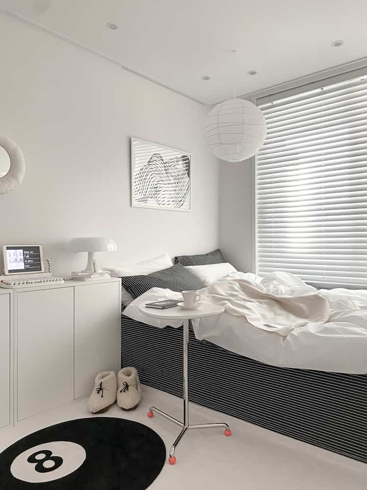 White and black toned modern bedroom for a single household featuring an 8-ball rug and a clean bed-focused layout