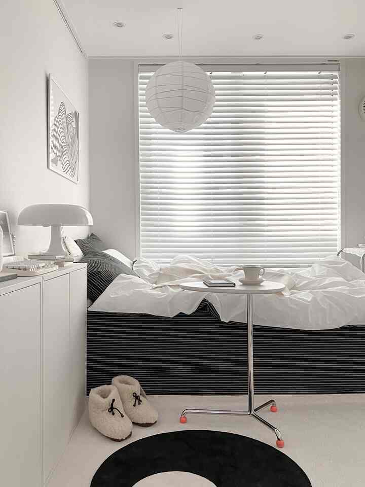 Monotone bedroom in white and black featuring a striped bed and minimalist table in a simple modern setting