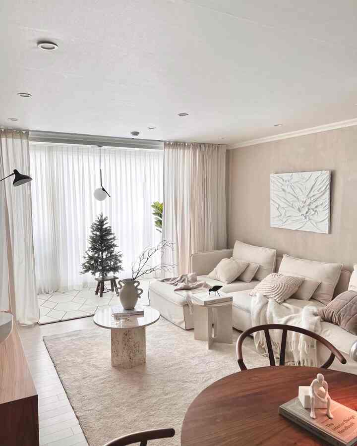 明るいホワイトとベージュの色調のリビング、ベージュのコーナーソファと丸いコーヒーテーブルが配置されたナチュラルモダンな雰囲気のインテリア