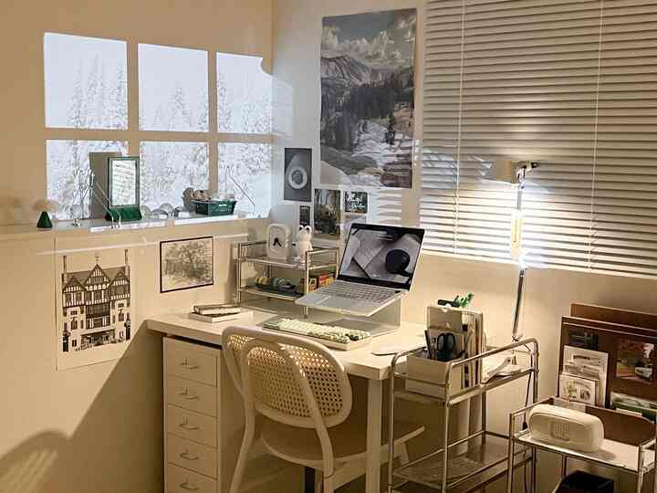 White and beige toned home office featuring a wooden chair, clean desk, and organized wall art with a calm workspace atmosphere