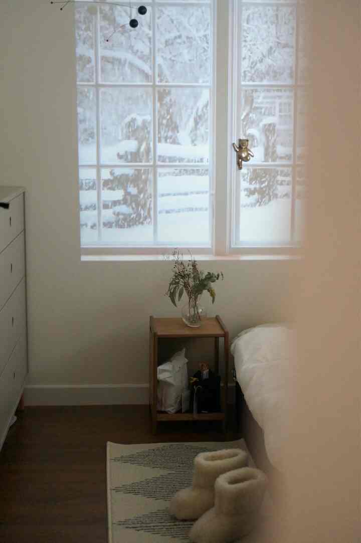 アイボリーと木目調の6畳寝室、サイドテーブルと室内履きが配置された雰囲気のあるインテリア