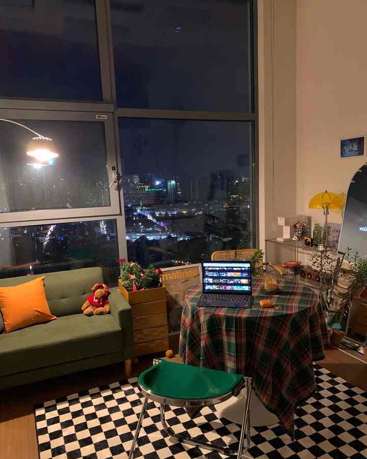 A cozy studio living room in orange and green tones featuring mid-century modern sofa and plaid tablecloth