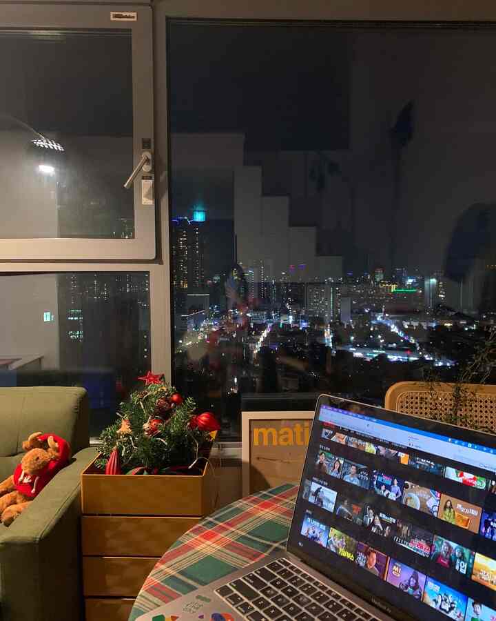 Living room with white walls and green sofa, featuring a checkered tablecloth and Christmas decorations creating a cozy home office atmosphere
