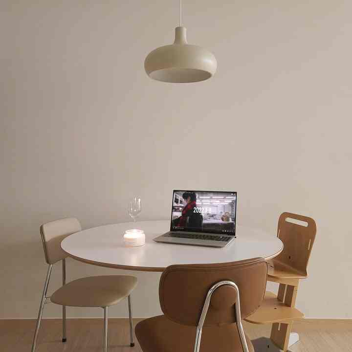 Minimal-toned dining room with white and wood tones, featuring a round dining table and varied chairs in a neat space