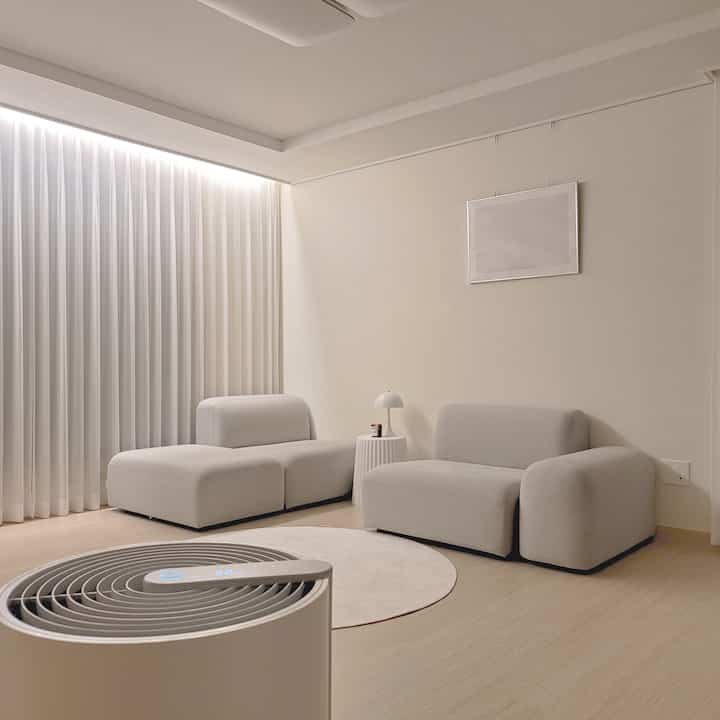 Bright white and natural wood tone modular living room featuring minimalist modern furniture arrangement