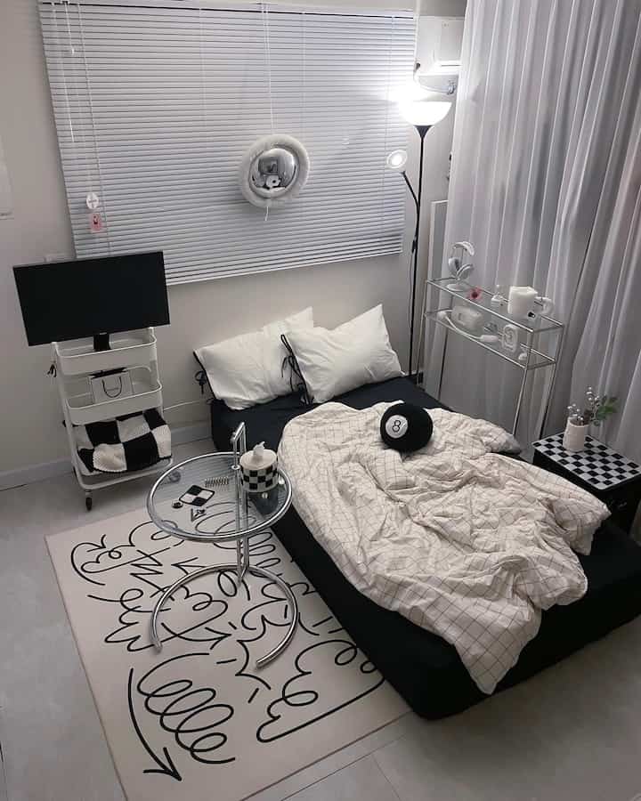 モノトーンの白と黒が調和したワンルームの寝室、ブラインドとモダン家具が配置された雰囲気のあるインテリア