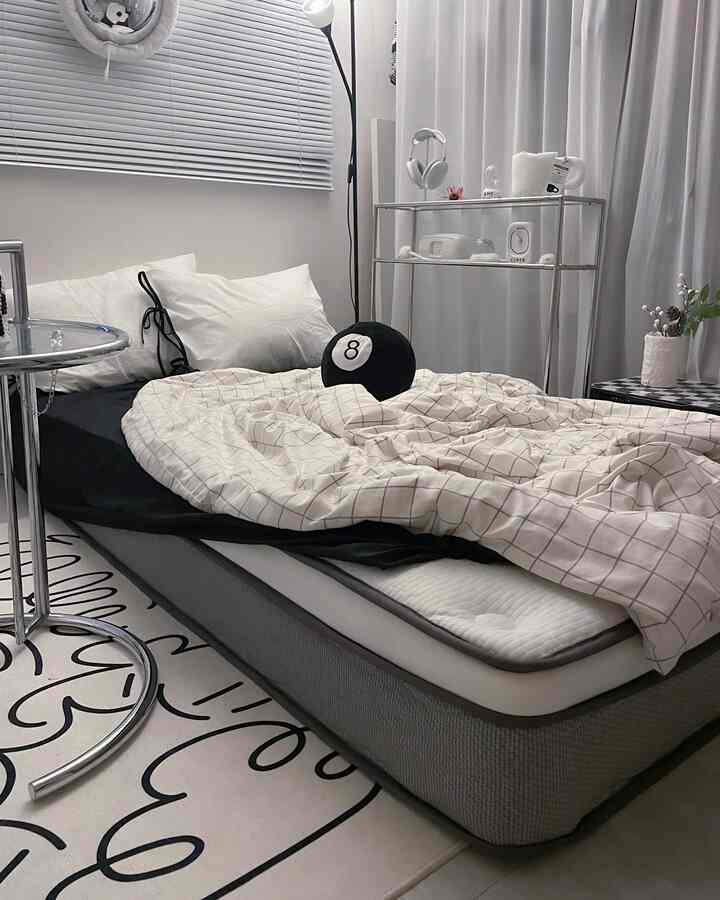 A modern studio bedroom featuring white and black hues, neat mattress and bedding creating a clean atmosphere
