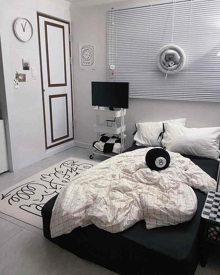 White and black toned studio bedroom featuring blinds, mattress with bedding, creating a simple and minimal atmosphere