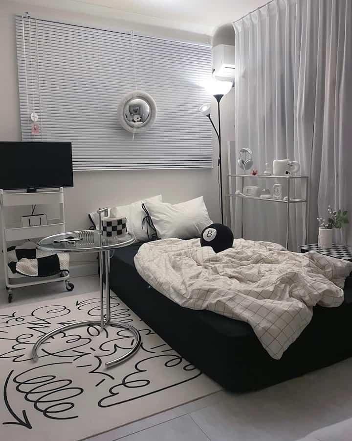 White and black toned studio bedroom with blinds and modern furniture creating a cozy atmosphere