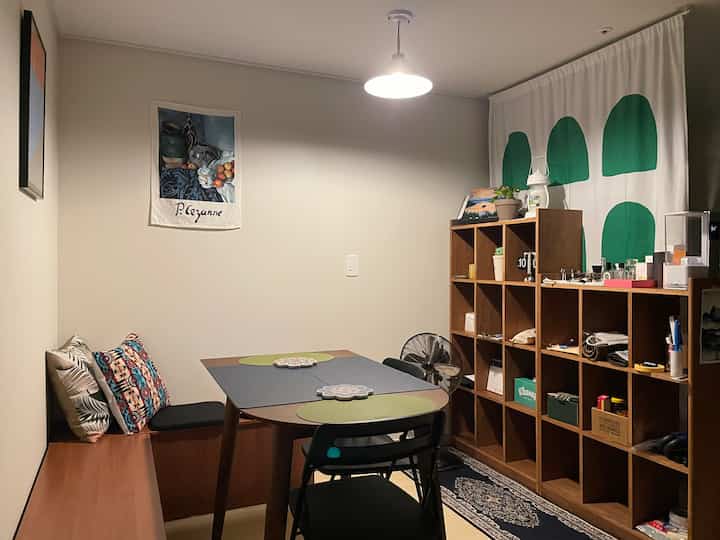 Wood tone and white toned dining room featuring a bench, chairs, and organized bookshelf in a simple setting