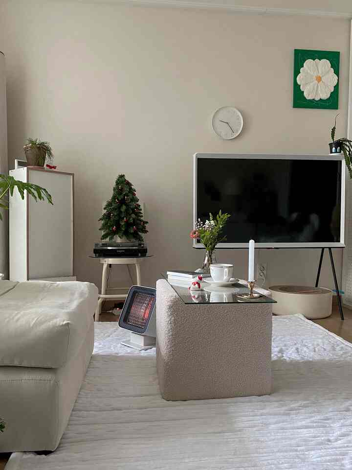 White and wood-tone living room featuring a Christmas tree and electric heater creating a cozy atmosphere