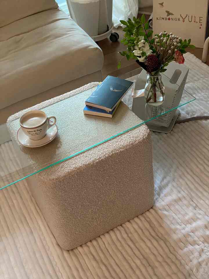 Natural-colored living room featuring beige sofa, glass coffee table with vase and coffee cup, creating a cozy atmosphere