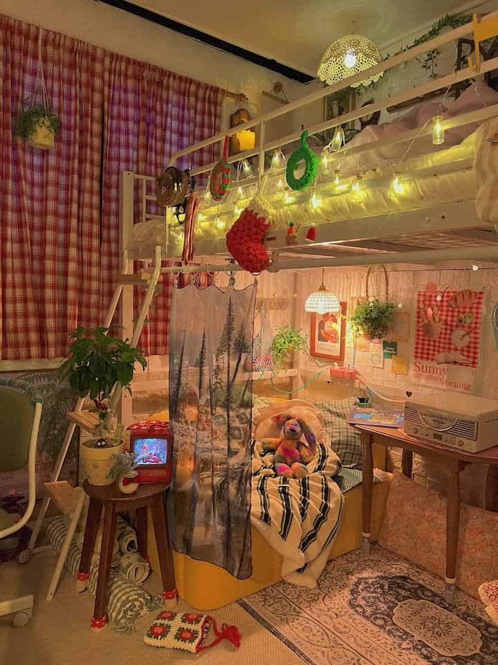 Warm yellow-lit bedroom for two featuring red check curtains and cozy Christmas decorations creating a festive atmosphere