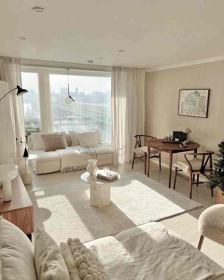 Bright white and wood tone living room featuring sofas, a coffee table, and armchairs with a warm natural atmosphere