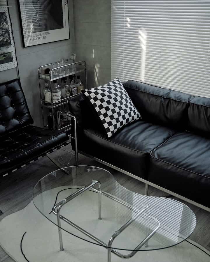 Modern black and white toned living room featuring leather two-seat sofa and glass coffee table in a clean setting