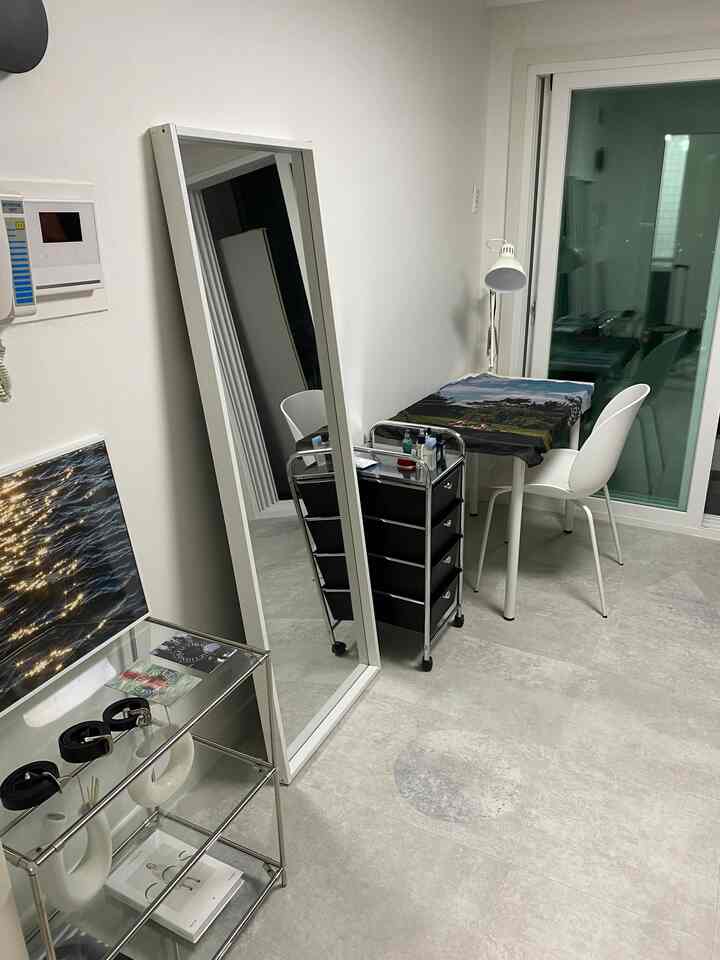 白い壁とグレーの床が特徴のコンパクトなダイニングルーム、全身鏡やミッドセンチュリーモダンの引き出しトロリーを配した北欧風の雰囲気あるインテリア