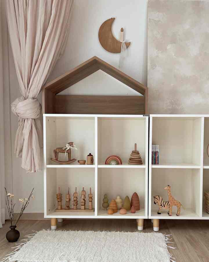 A clean baby room in white and wood tones featuring kids' furniture and decorative objets in a natural style